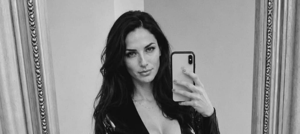 Alt text:
Black-and-white mirror selfie of Lady Victoria with dark hair, holding a smartphone and looking confidently into the mirror.