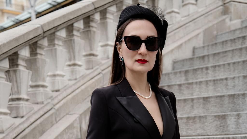 Mistress Severna, Dominatrix in Lausanne, Geneva, and Zurich, wearing an elegant black outfit on a stone staircase.