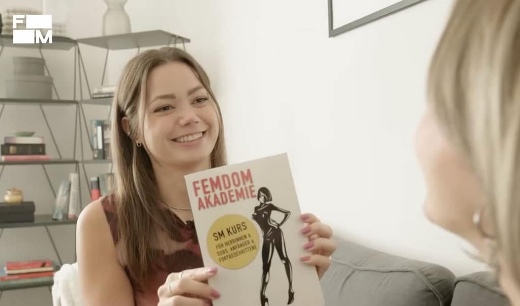 Domina Franzi empfiehlt in der FUNK-Reportage ‚So ist der Job als Domina‘ das Buch Femdom Akademie von Lady Sas. Quelle: FUNK / ARD & ZDF