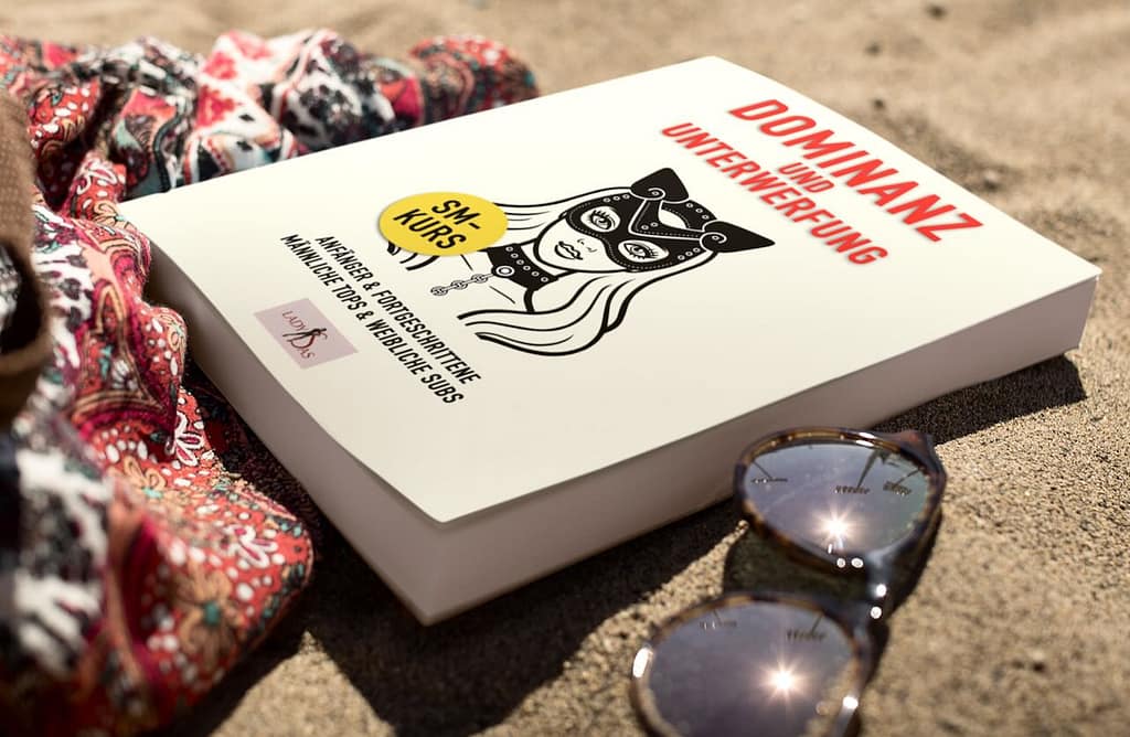 Dominanz und Unterwerfung Buch: Das Buch liegt an einem Sandstrand.