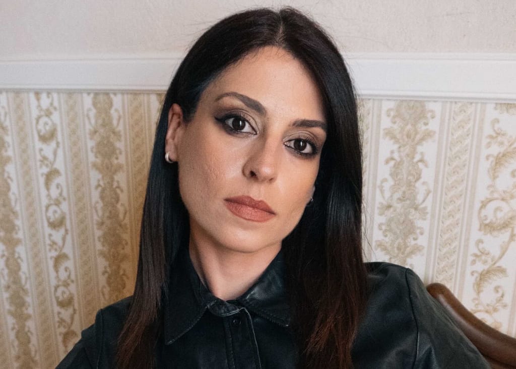 Mistress Aido Akida, a Berlin-based dominatrix, wearing a black leather top and looking directly into the camera.