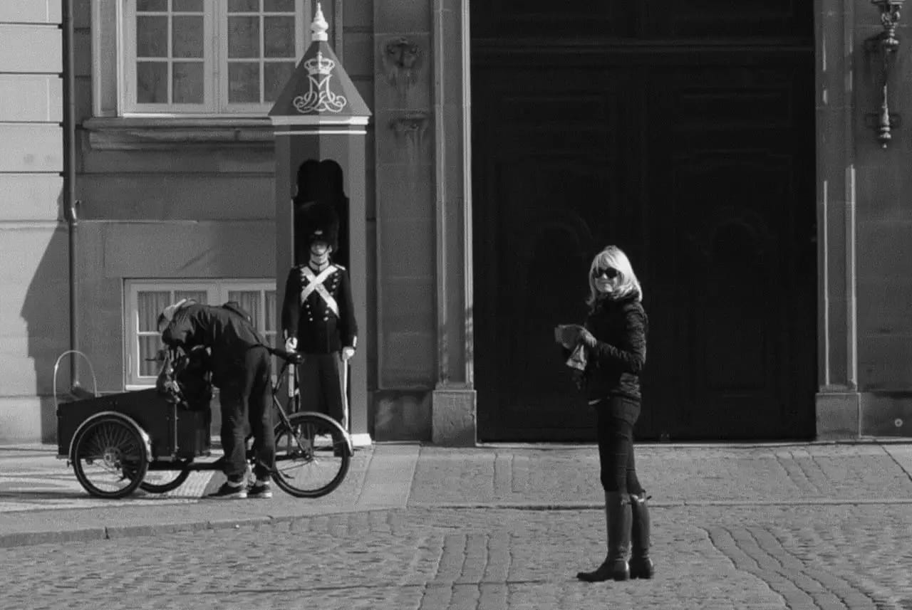 Alt text:
Black-and-white travel photo of Lady Sas standing in Copenhagen in front of a historic building.