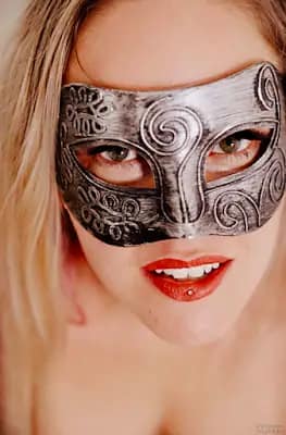 Switch Aglaya wearing a decorative black mask in a close-up BDSM portrait.