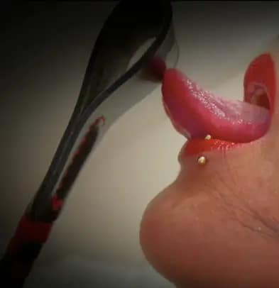 Private Femdom Ms Femme Fatale from Dortmund licking the tip of a riding crop.