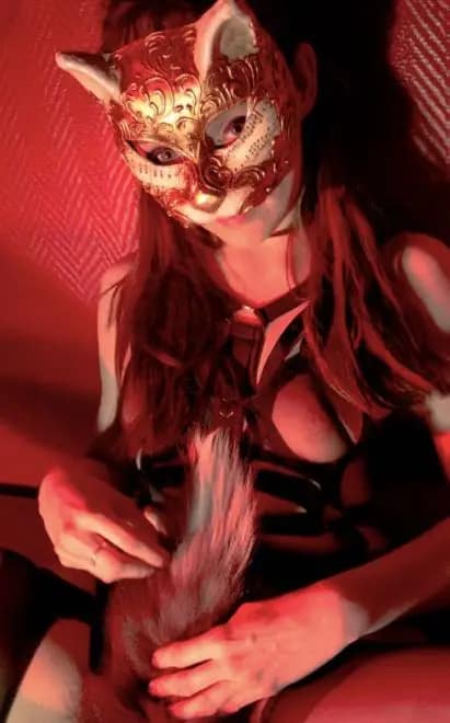 Female Studio Slave Usagi from Berlin wearing an ornate cat mask during pet play.