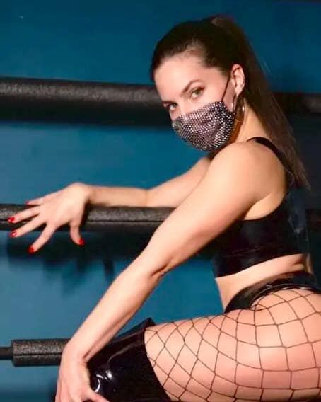 Goddess Aviva, Dominatrix in New York City, wearing black lingerie, fishnet stockings and a jeweled face mask