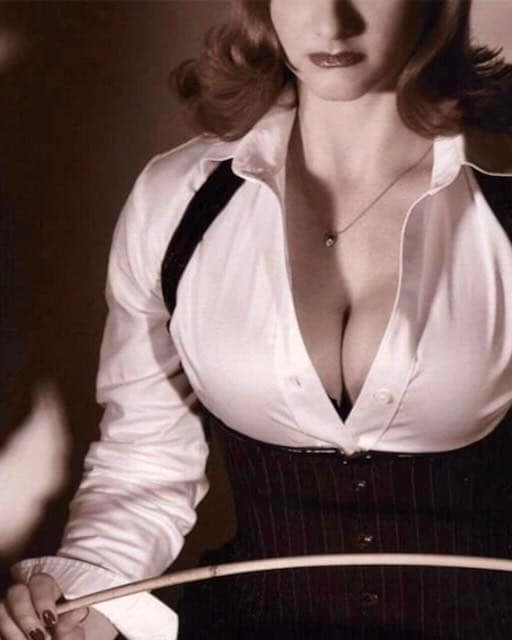 Miss Georgia Payne, Dominatrix in Los Angeles, holding a cane in a white blouse and black corset