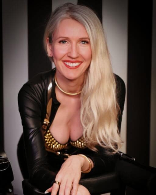 Miss Devianz, a Hamburg-based Fetish Mistress, wearing a black and gold fetish outfit