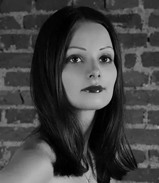 Mistress Arella, Prager Dominatrix und ehemalige OWK-Lady, als Schwarz-Weiß-Porträt vor einer Ziegelwand.