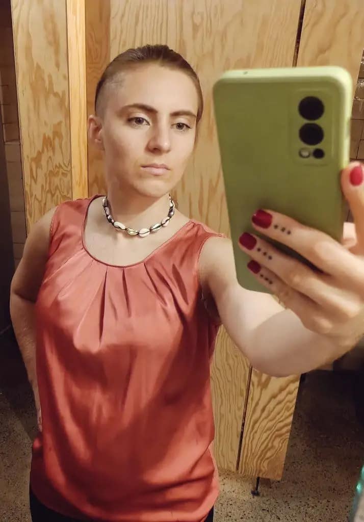 Miss Juli from Zurich, Switzerland, taking a mirror selfie in a soft pink top.