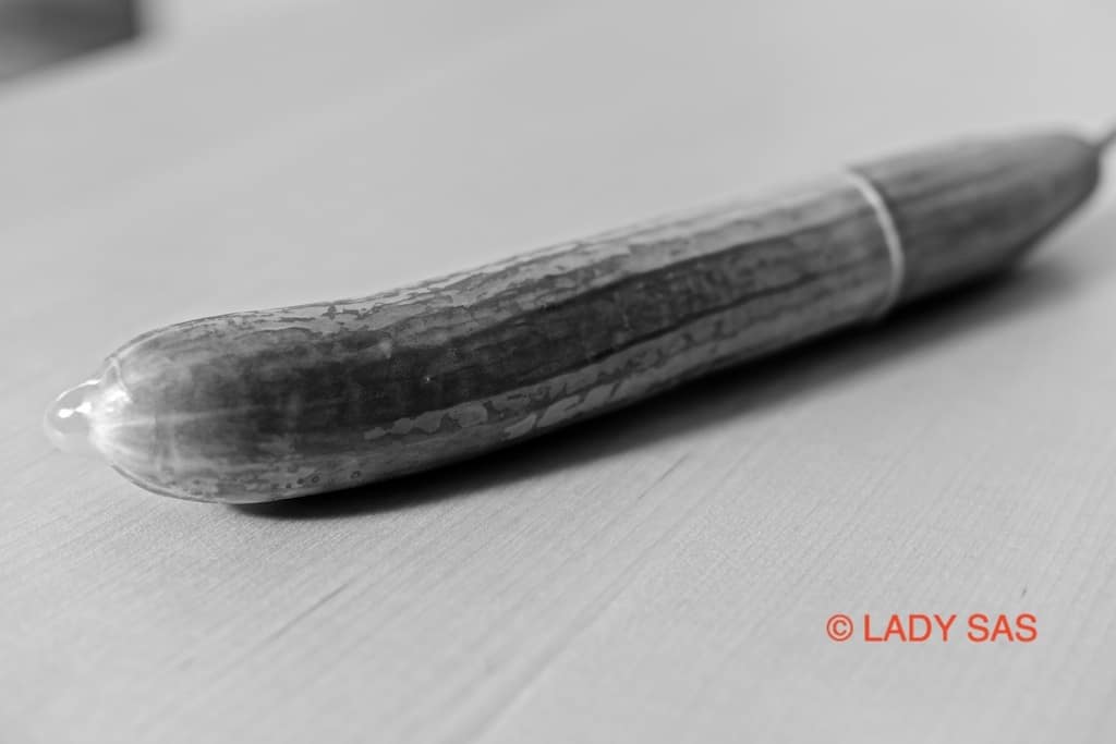 Eine große Gurke ist mit einem Kondom überzogen und bereit für ein Pegging.